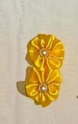 imagem de um laço de cabelo amarelo simulando uma flor com bolinhas de miçanga no centro da flor